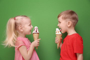 Cute little children eating ice cream on color background