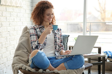 Beautiful young woman using laptop at home