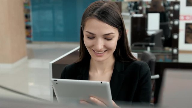 Smiling mature professional businesswoman in office. Holding a digital tablet . Woman brunette in airport or shopping mall