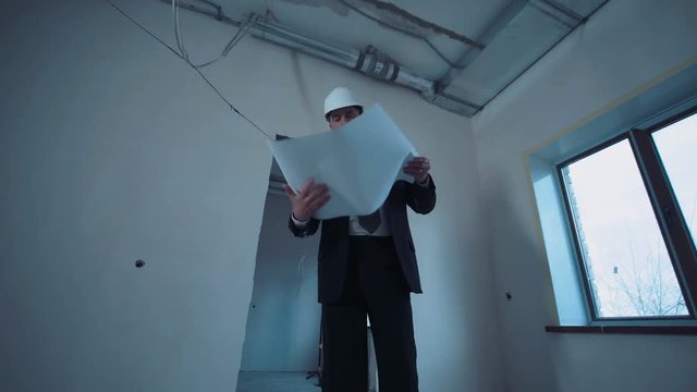 A taskmaster walking on a construction site with the plan.