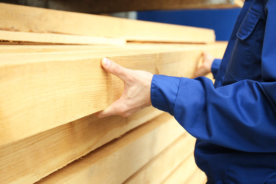 Carpenter with wooden planks in workshop, closeup