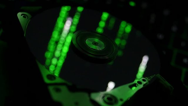 Close-up shot of interior of computer hard drive with matrix style code in the reflection.