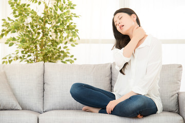 woman sitting on sofa with neck pain