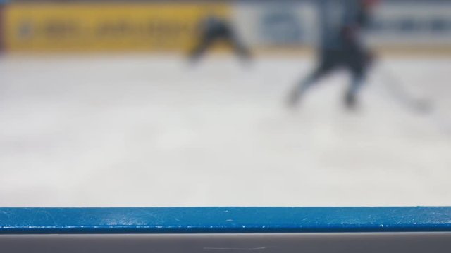DEFOCUSED BACKGROUND blurred ice hockey game in indoor stadium. Board in focus. 4K UHD