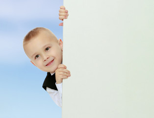 boy peeks out from behind the banner