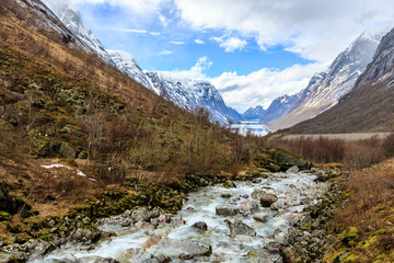 Fototapeta na wymiar Water flow down from river to lake with snow cap mountain background