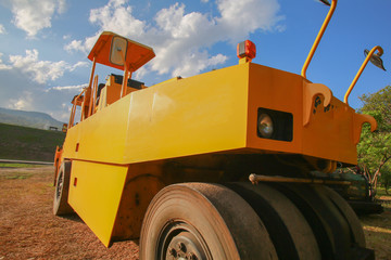 Road roller at road construction site with cloudy blue sky during sunset