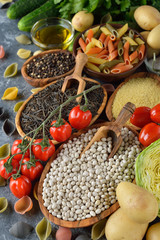 Raw ingredients for vegetarian cuisine on a gray background