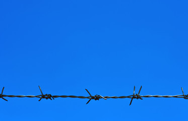 Barbed wire fence against the blue sky
