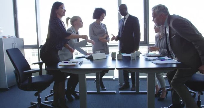 Two business colleagues shaking hands across the table in congratulations during a multiracial business meeting at a conference table in the office