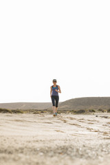 Athletic Lady Running in the Desert with White Sky Background