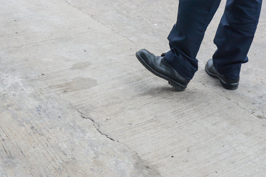 Leg of man with long black trousers standing on the street., security guard men shoes stand on walking street