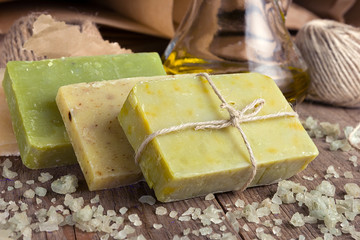 Collection of handmade, natural organic soap and cosmetic oil on wooden background. Spa products. Purple tinted