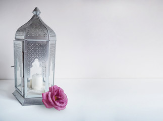 Ornamental silver Arabic lantern with rose flower on the table. Greeting card, invitation for...
