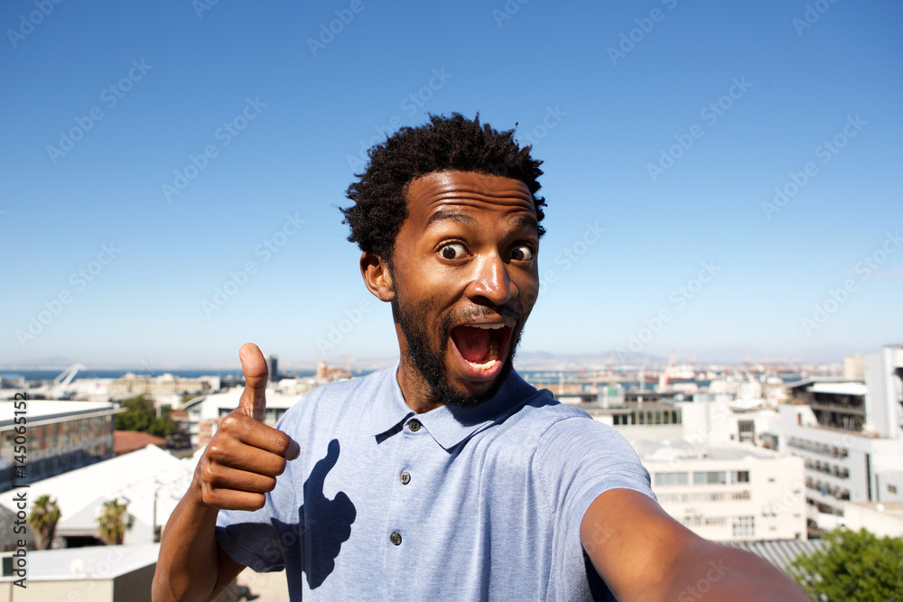 Wall mural african american man standing by urban background with thumb up