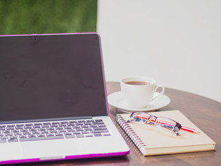 Workplace with laptop coffee and book on wooden desk.