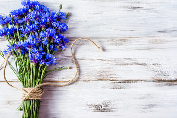 Blue flowers, summer wildflowers bouquet on white wooden background, copy space