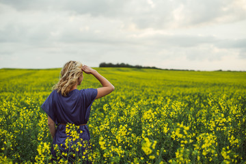 Young woman standing outdoor in rapeseed flower field