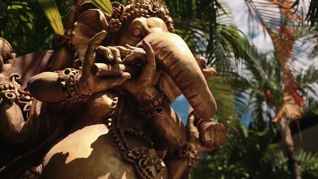 Big statue of hindu deity Ganesha between trees, Bali. Medium low angle shot with Sony a7s on slider on sunny summer day