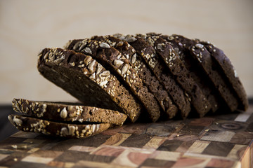 Black bread with seeds and sesame seeds on a board of wooden logs