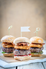 Small beef sliders grilled burgers onion rings little buns bacon served as appetisers for sharing 