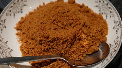 Brown sugar in a plate with metal silver spoon