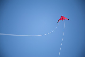 Blue sky, and flying red kite and white strings