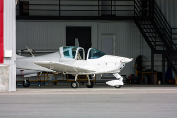 Small sports plane with opened cockpit canopy in the hangar