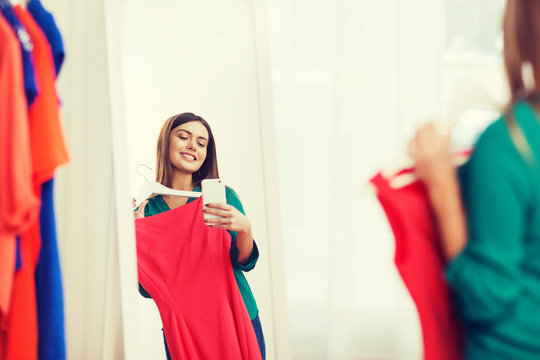 woman with smartphone taking mirror selfie at home