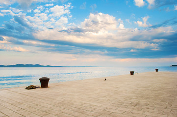 Stone tiles pavement near the sea shore against the background of a hill range and dramatic cloudy...