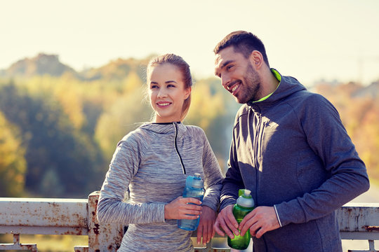 smiling couple with bottles of water outdoors