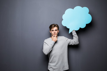 Man with hands on chin holding blue blank speech bubble with space for text on grey background