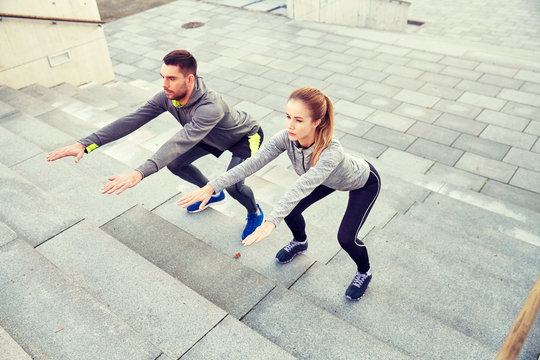 couple doing squats on city street stairs