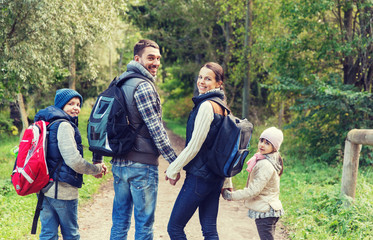 happy family with backpacks hiking in woods