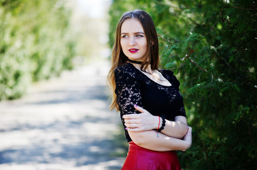 Portrait of girl with bright make up with red lips, black choker necklace on her neck and red leather skirt.