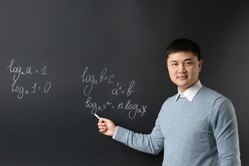 Handsome young Asian teacher on blackboard background