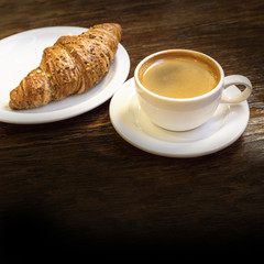 Cup of dark coffee with cereal croissant