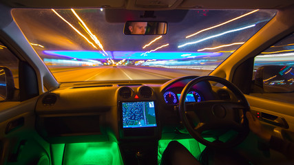 The man drive in the road with a navigation. Evening night time. Inside view