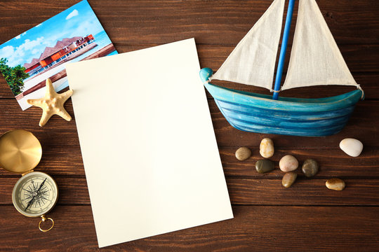 Travel concept. Blank notepad page, compass and cute sea decorations on wooden background
