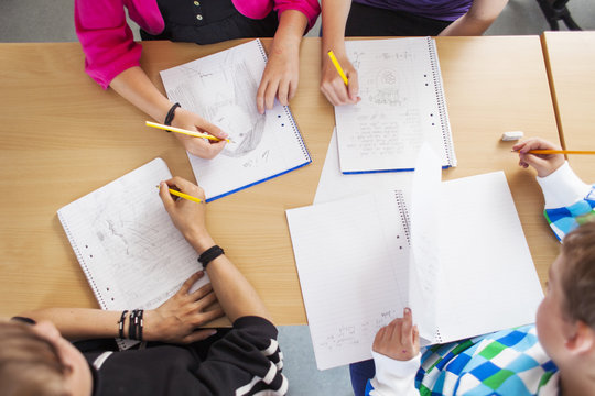 High angle view of junior high students studying at desk in classroom