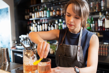 barmaid with glass and jug preparing cocktail