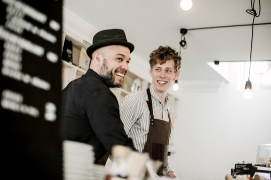 Smiling male baristas working in coffee shop