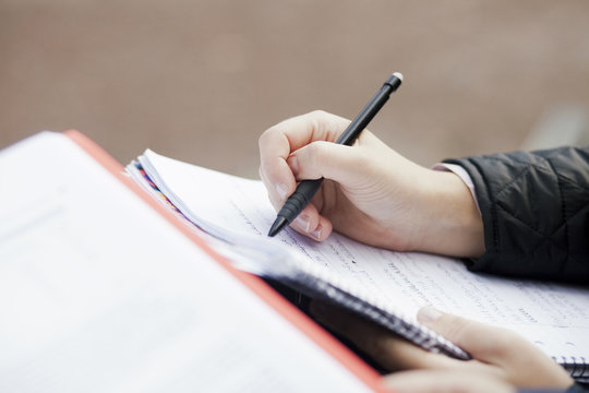 Cropped hand of woman writing in book