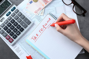 Woman making notes in notebook, closeup. Tax refund concept