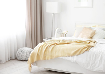 Fototapeta na wymiar Comfortable bed with soft beige coverlet and pillows in light modern room