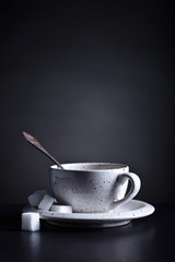 Cup of coffee with sugar on dark background