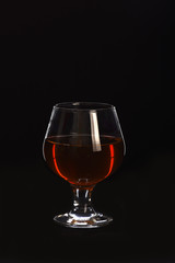 glass with cognac or whiskey isolated on black background