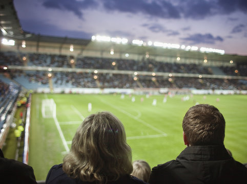 Rear view of people watching soccer match at stadium