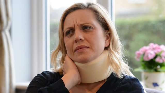 Mature Woman Wearing Neck Brace Winces With Pain