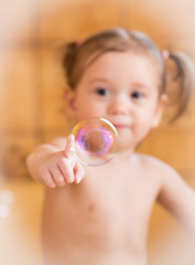 Catching soap bubbles.Adorable little girl in bathtub trying to catch soap bubbles